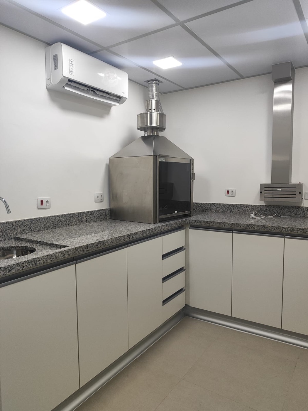 Bancada em L com tampo de granito, cuba de inox e capela de exaustão